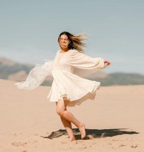 Woman in a white dress dancing on the sand