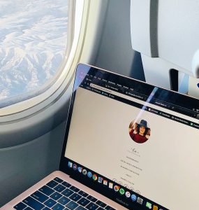 An open laptop on a plane with view of mountains